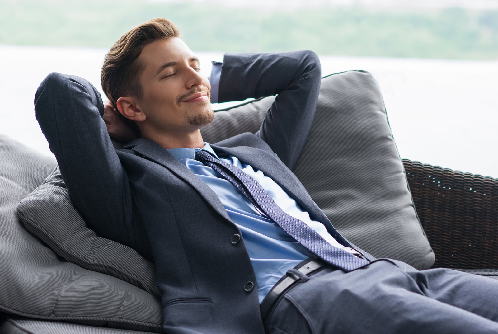 smiling-man-with-hands-behind-head-dozing-on-couch